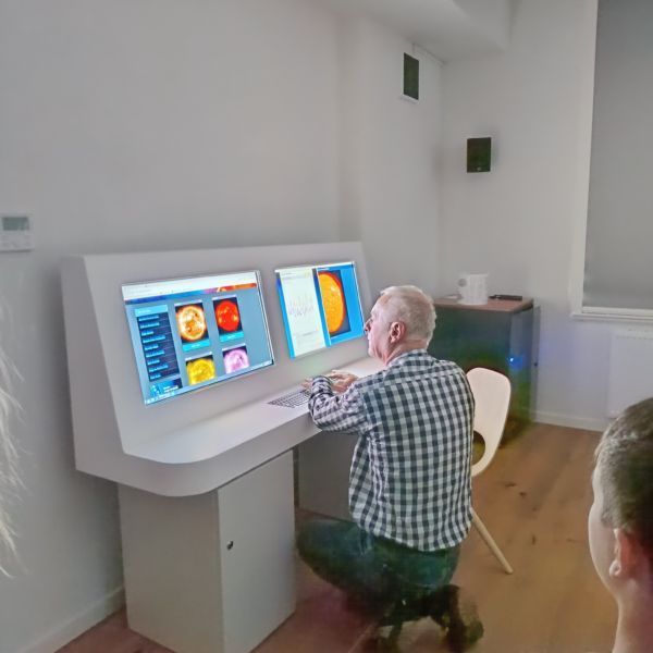 na zdjęciu mężczyzna przewodnik pokazuje na komputerach zainteresowanym jak wyglądają planety