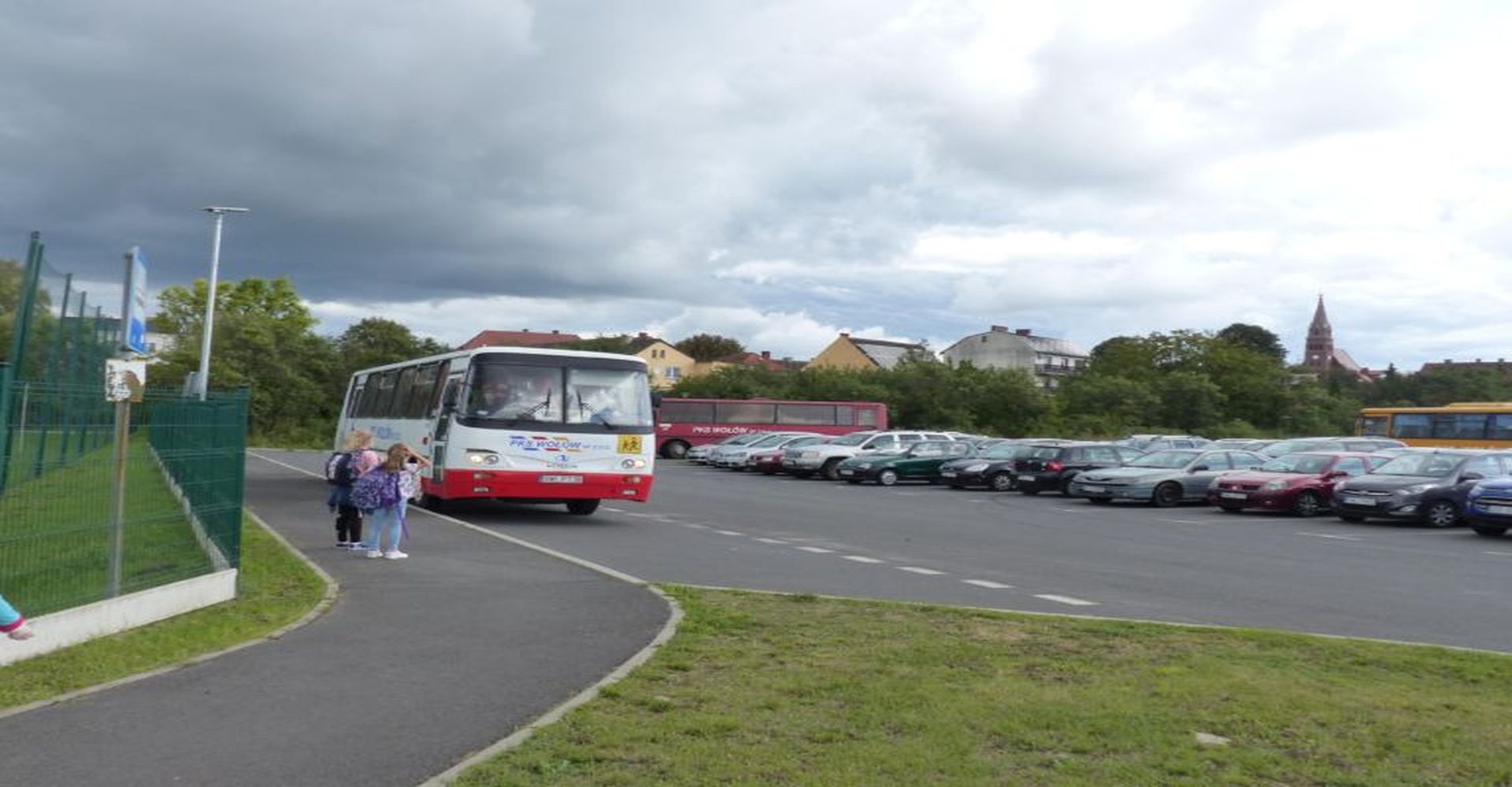 na zdjęciu autobus szkolny, a koło niego dwie dziewczynki które czekają na kurs